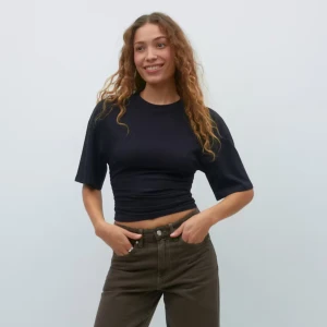 Svart croppad t-shirt - En svart croppad t-shirt med korta ärmar och rund halsringning. T-shirten har en tight passform och är perfekt att matcha med jeans eller kjol för en avslappnad stil.