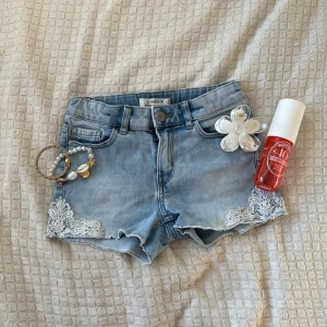 Ljusblå jeansshorts med spets från Lindex - Säljer ett par ljusblå jeansshorts från Lindex med fina spetsdetaljer vid bensluten. Shortsen har storlek 128 men har passat 146 jätte bra! Älskar dom men har blivit för små❤️ priset för att diskutera!!