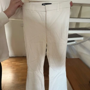 Vita bootcut byxor från Zara XS - Snygga vita bootcut-byxor från Zara i storlek XS. Byxorna har hällor för bälte, raka fickor bak och är tillverkade i ett mjukt bomullsliknande material. Perfekta för en clean och fräsch look.