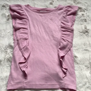Rosa volangtopp från Kappahl - Supersöt ljusrosa topp från Kappahl med volanger, storlek 170 , ( har en liten fläck med jag ska tvätta bort det ) pris 15 kr🥰