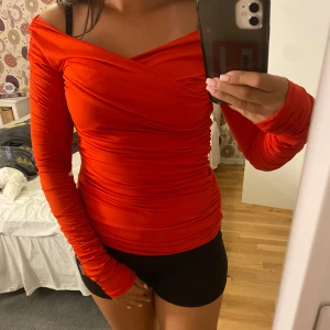 Röd omlott offshoulder topp H&M - Säljer en snygg röd omlottopp från H&M med offshoulder och långa ärmar. Toppen har tight passform och är gjord i ett stretchigt, mjukt material som sitter skönt mot kroppen. Perfekt för dig som vill sticka ut med en färgstark look!