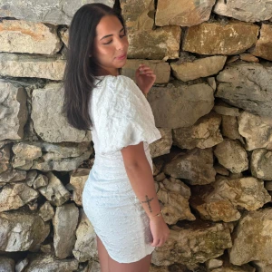 Vit kort klänning med puffärm - Superfin vit kort klänning med puffiga ärmar och strukturerat tyg. Sitter tajt och har en snygg passform!  Den är knappt använd. Storlek 34💕