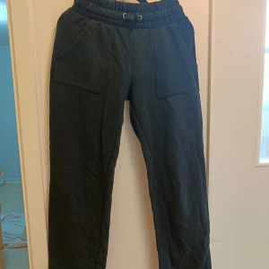 Svarta mjukisbyxor med fickor - Svarta mjukisbyxor med bred resår i midjan och dragsko. Byxorna har stora fickor både fram och bak, raka ben och är gjorda i mjukt bomullstyg. Perfekta för chill dagar eller när du vill vara bekväm.