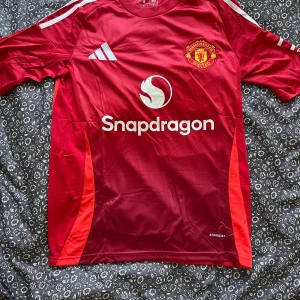 Manchester United röd matchtröja Adidas - Snygg Manchester United fotbollströja från Adidas i röd färg med vita detaljer och logga på bröstet. Inget namn på ryggen🙂‍↕️