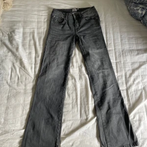 Grå bootcut jeans från 157 - Snygga grå jeans från 157 i modellen 90's Boot. Jeansen har klassisk femficksdesign, bootcut-ben och råa, slitna kanter nertill för en cool vintagekänsla. Perfekta för dig som gillar en avslappnad och trendig look. Köpare står för frakt 