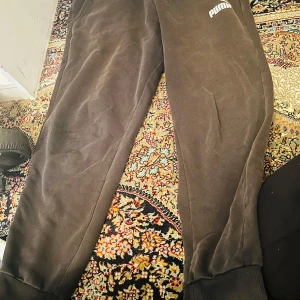 Svarta mjukisbyxor från Puma L - Svarta mjukisbyxor från Puma i storlek L. Byxorna har resår i midjan, muddar vid bensluten och två sidofickor. Puma-logga i vitt på ena benet. Perfekta för chill eller träning.