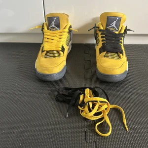 Nike Air Jordan 4 Retro Tour Yellow - Gula Nike Air Jordan 4 Retro Tour Yellow med svarta och grå detaljer. Ovandel i mocka, meshpaneler och klassisk Jumpman-logga på plös och häl. Skorna har både gula och svarta skosnören men de gula är originala och de svarta la jag till för att ha en Nice missmatch för en cleanere look(plus et par till svarta och gula snören till skorna fins på första bilden), samt vit och grå sula med synlig Air-enhet. Perfekt för dig som vill sticka ut. Ingen låda‼️