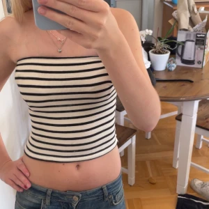 Randig bandeau tubtopp Gina Tricot XS - Säljer en ribbad bandeau tubtopp från Gina Tricot i storlek XS. Toppen är svart, vit randig och har en croppad passform. Använd fåtal gånger, mycket bra skick!💕