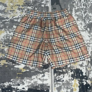 Rutig Burberry shorts i beige S - Snygga Burberry shorts i klassiskt rutigt mönster med beige, svart, vit och röd. De har elastisk midja och är tillverkade i lätt polyester, perfekt för sommaren. Ikonisk design som ger en cool vibe till din outfit.