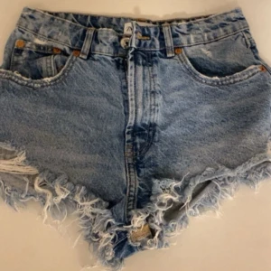 Blå jeansshorts med fransig kant från Zara - Snygga blå jeansshorts från Zara med hög midja och fransig kant. Passar på mig som har 36. Köranden betlar frakt!