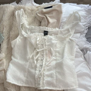 Vit blommig korsettopp från SHEIN BAE - Supersöt vit korsettopp från SHEIN BAE med broderade blommor, knappar och snörning framtill. 🥰