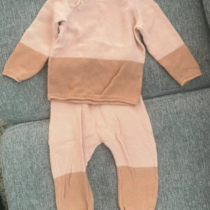 Beige och brun stickad tröja barn - Säljer en söt stickad tröja för barn i beige och brunt. Tröjan har långärmade raglanärmar och två knappar vid axeln för enkel påklädning. Färgerna är mjuka och passar perfekt till höst och vinter. Materialet är stickat och känns mjukt mot huden. 18-24 månader/ 86 cm.