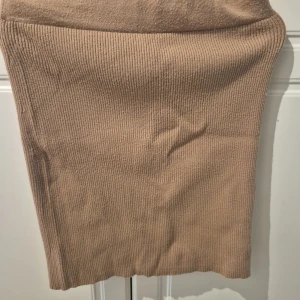 Beige ribbad kjol från Amisu - Säljer en beige ribbad kjol från Amisu i stickat material. Kjolen är kort och har en slim passform som sitter snyggt. Perfekt för dig som gillar en enkel men trendig look. Storlek EU 36.