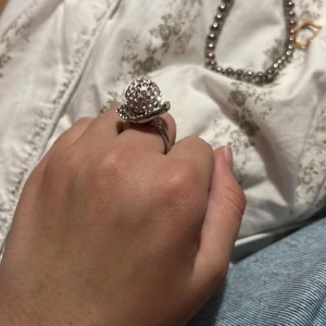 Glittrig silverring med pärlor - Säljer en unik silverring med stor rund topp täckt av glittriga pärlor. Ringen har en cool och iögonfallande design som verkligen sticker ut. Perfekt för dig som vill ha något extra till din stil. Storleken är justerbar och passar de flesta.