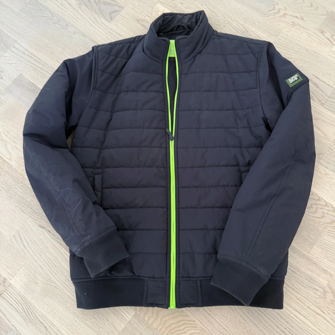 Svart pufferjacka med grön dragkedja