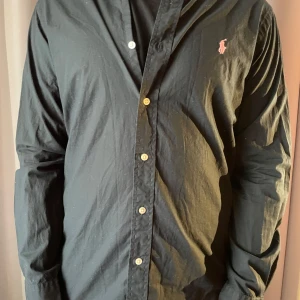 Ralph Lauren Skjorta  - Svart skjorta från Ralph Lauren i slim fit med klassisk krage och knäppning framtill. Tillverkad i 100% bomull med stretch för extra komfort. Skjortan är i riktigt bra skick🤗Priset är ej hugget i sten🤗