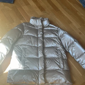 pufferjacka med dragkedja - Säljer en pufferjacka från mango i storlek XS. Jackan har hög krage, dragkedja och tryckknappar framtill samt två fickor. Materialet är glansigt och jackan är vadderad för extra värme. Perfekt för dig som inte vill frysa i vinter! Pris han diskuteras💞💞