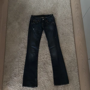 True Religion mörkblå bootcut jeans - Mörkblå low waist bootcut jeans från True Religion i jättefint skick! Lite slinta ner till bara (kolla sista bilden). Tyvärr för små för mig ❤️waist 24 (innerbenslängd: 83cm midja: 35cm) Pris kan förhandlas!