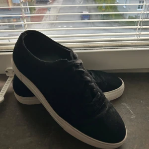 Axel Arigato skor - Snygga svarta sneakers med vit sula och ovandel i mjuk mocka. Klassisk rund tå och snörning framtill. Strl 44