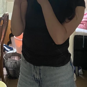 Svart/Grå ärmlös topp från H&M - En svart/grå, enkel och tight topp från H&M med ärmlös design och rund halsringning. Toppen är i mjuk bomull och har en lätt rynkad effekt i sidorna som ger en snygg passform. Perfekt att matcha med jeans eller kjol för en clean look.