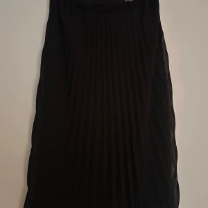Svart plisserad långkjol - Snygg svart långkjol med plisserade veck. Resor i midjan.