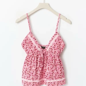 Blommig rosa linnetopp från Gina Tricot - Supersöt rosa linnetopp med små röda och rosa blommor, spetsdetaljer och knyt framtill. Tunn och luftig med smala axelband och v-ringad hals. Använd fåtal gånger så är i nyskick. Helt slutsåld på hemsidan💗