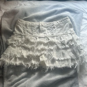 Vit jeanskjol med volanger från Monki - Supersnygg vit kortkjol från Monki i jeansmaterial med flera lager fransiga volanger. 