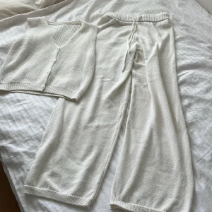 Vit stickad väst med knappar - Vit stickad väst med v-ringning och knäppning framtill. Västen har ribbade kanter nedtill och vid ärmöppningarna, vilket ger en clean och stilren look. Perfekt att styla över en t-shirt eller skjorta för en chill vibe. Ett set från mango 