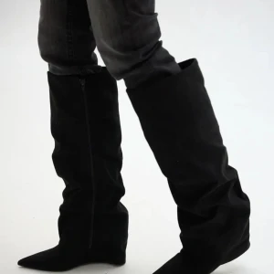 Svarta stövlar med spetsig tå - Snygga svarta stövlar i mocka-look med spetsig tå och låg klack. Stövlarna har dragkedja på sidan, rynkad design som ger en cool vibe. Perfekta att styla med jeans eller kjol för en trendig look.