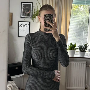 Grå ribbad långärmad klänning - Säljer en tight, gråmelerad ribbad klänning med lång ärm från Gina tricot. Klänningen är kort och har ett smickrande slim fit. Perfekt för dig som gillar en enkel men stilren look.