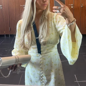 Gulblommig kortklänning från adoore - Superfin kort klänning från By Malina i ljusgul med  figursydd midja🥰 Klänningen är gjord i ett strukturerat tyg som känns lyxigt och somrigt. ENDAST använd 1 gång till min examen inget slitage alls. Är 160cm 🥰 är i vanliga fall S/36 men pga den insydda midjan är 38 bra storlek.