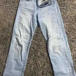  jeans  - Säljer ett par ljusblå mom jeans i straight fit med klassisk femficksdesign. Jeansen har hög midja och raka ben, perfekt för en avslappnad och trendig look. Tillverkade i bomull för skön känsla och snygg passform.