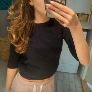 Svart stickad croppad topp - En svart stickad topp med trekvartsärm och croppad passform. Enkel och stilren design som är lätt att matcha med olika outfits. Mjuk och skön att bära, perfekt för dig som gillar en clean look. Från Zara! 💕passar xs