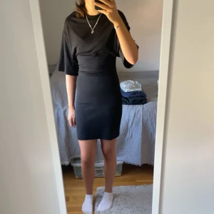 Svart kortklänning med vida ärmar - En svart, enkel och stilren kortklänning med loose passform upptill och tightare kjol. Klänningen har vida, korta ärmar och rund halsringning. Perfekt för dig som gillar minimalistisk stil. Går att klä upp och klä ner! Helt ny med prislapp och enbart testad. Säljer då jag tappat bort kvittot. Nypris 359