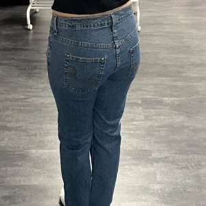 Blå jeans med broderade bakfickor - Snygga blå jeans med klassisk femficksdesign och broderade detaljer på bakfickorna. Jeansen har normal passform och midwaist, tillverkade i slitstarkt denim. 98% Bomull. Är 163 cm för referens😊😊
