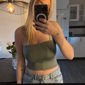 Olivgrön croppad tubtopp - Säljer en olivgrön croppad tubtopp från Bershka. Toppens material känns mjukt och stretchigt! Köpt i Spanien och knappt använd, strl S!💚