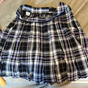 Lila och svart rutig kjol Lindex - Superfin kortkjol från Lindex i rutigt mönster med lila, svart och vitt. Kjolen har klassisk A-linjeform och är perfekt för dig som gillar en cool och trendig stil. Passar dig som är 14 år eller äldre.