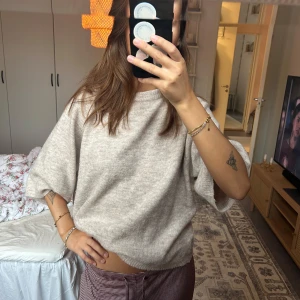 Beige stickad tröja med vida ärmar - Säljer en beige stickad tröja med breda, trekvartsärmar och avslappnad passform. Tröjan har en mjuk och mysig känsla, perfekt för lager-på-lager och chill dagar. Enkel design som är lätt att matcha med olika outfits.