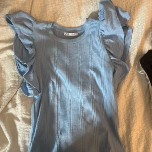 Blå Zara topp - Säljer denna super fina blåa Zara toppen med volanger! Den är i storlek S och är aldrig använd, ny utan prislapp!🥰