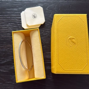 Swarovski silverfärgat armband - Superfint armband från Swarovski i silverfärg med gnistrande stenar längs hela ytan. äkta kristaller. Kommer i original gul ask med logga 🤍