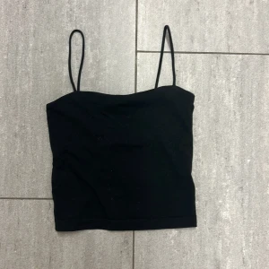 Svart linnetopp från Gina Tricot XS - Enkel och stilren svart linnetopp från Gina Tricot i storlek XS. Toppen har tunna axelband och rak skärning, perfekt att matcha med jeans eller kjol. Mjuk och stretchig bomullskänsla som sitter snyggt på kroppen.
