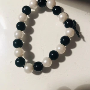 Svartvitt pärlarmband med elastisk tråd - Stilrent armband med stora pärlor i svart och vitt, trädda på elastisk tråd. Perfekt accessoar för att ge din outfit en klassisk touch. Pärlorna är runda och har en glansig finish. Hand gjord 
