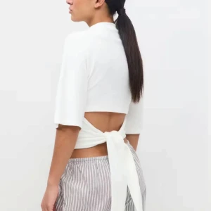 Vit croppad topp med knyt i ryggen - Superfräsch vit croppad topp med halvlånga ärmar och snygg öppen rygg som knyts med breda band. Perfekt för varma dagar när du vill ha en stilren men cool look.