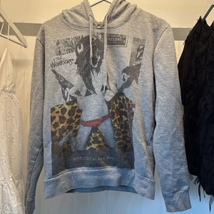 Grå hoodie från IRO med tryck - Säljer en grå hoodie från, life is a joke, med coolt tryck framtill som har leopardmönster och grafiskt motiv. Tröjan har huva med snörning och är långärmad. Perfekt för dig som gillar streetstyle och vill sticka ut lite extra.