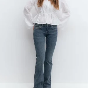 Blå bootcut jeans låg midja - Snygga blå bootcut jeans med låg midja och figurnära passform. Jeansen har utsvängda ben, klassiska fickor fram och bak samt dragkedjegylf. Stretchigt material för extra komfort och coola detaljer på bakfickorna.