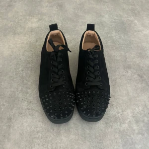 Cristian loubs - Svarta sneakers i mocka med coola svarta nitar över tån. Skorna har snörning och en platt sula, vilket ger en edgy vibe. Insidan är ljusbeige och de har en klassisk rund tå. Perfekta för dig som vill sticka ut med din stil.