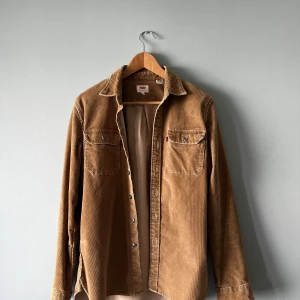Beige manchester skjorta från Levi's - Säljer en beige manchesterskjorta från Levi's i storlek S. Skjortan har två bröstfickor med knappar, klassisk krage och långa ärmar. Axelbredd: 44, längd: 71