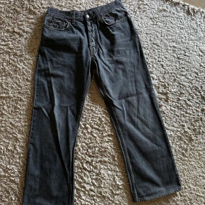 Gucci svarta raka jeans herr 49 - Snygga svarta jeans från Gucci i rak modell. Jeansen är tillverkade i 100% bomull och har klassiska fem fickor, silverfärgade detaljer och gul kontrastsöm. Perfekta för dig som gillar en stilren och tidlös look.