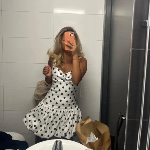 Vit kort prickig klänning - Supersöt vit kort klänning med svarta prickar och volangig kjol. Helt slut sold 💕 Använd endast en gång💕🥰Bilden är lånad men skriv gärna för flera bilder😚