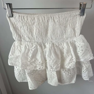 Vit volangkjol  - Supersöt vit kortkjol från Meet Me There med bred smock i midjan och flera lager volanger. Kjolen har broderade hål och spetsdetaljer. Säljs då den nästan aldrig kommit till användning, nypris är 455kr💕